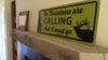 metal sign with a yellow background and black text saying 'the mountains are calling and i must go' on a mantle
