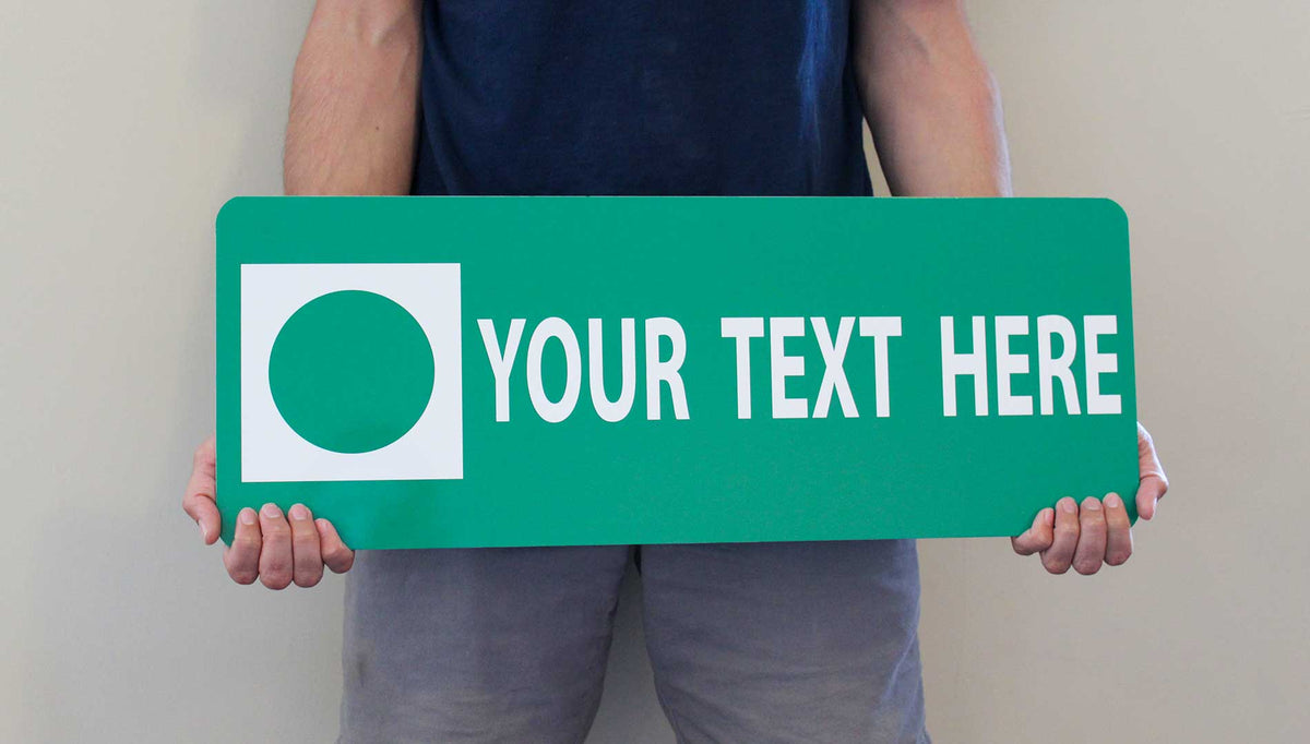 a man holding a custom metal green ski run sign with a green background and white text that says 'Your Text Here'