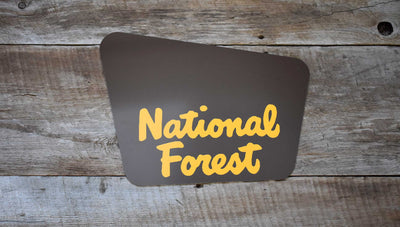 custom national forest sign with a brown background and yellow text that says 'national forest'