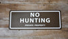 metal sign with a brown background and white text saying 'no hunting private property'