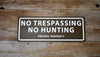 metal sign with a brown background and white text saying 'no trespassing no hunting private property'
