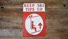 a metal sign with a white background and red text that says 'Keep Ski Tips Up' with an image of a skier on a chairlift