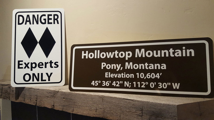 metal sign with black text saying 'danger experts only' with a two black diamonds on a white background on a mantle