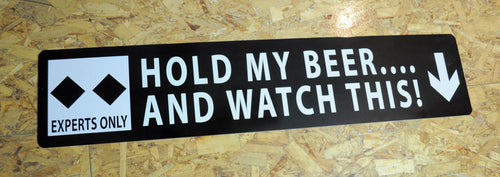metal sign with white text saying 'hold my beer...and watch this!' with a black background and two black diamonds