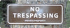 metal sign with white text saying 'no trespassing private property' with a brown background hung up on a tree