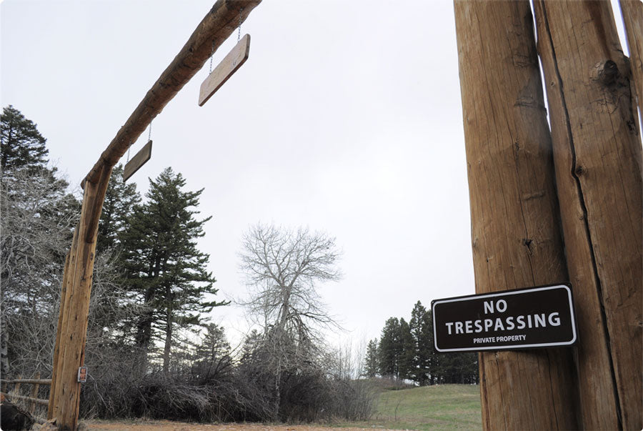 metal sign with white text saying 'no trespassing private property' with a brown background on an entrance way to a home